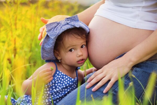 Mädchen lehnt sich an den Schwangerschaftsbauch der Mutter