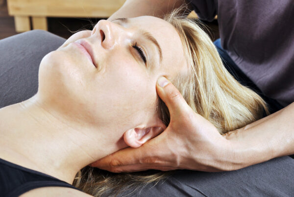 Eine Frau wird von einem Osteopath am Kopf behandelt.