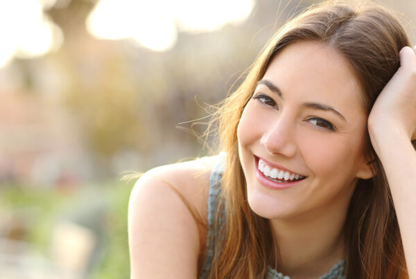 Eine Frau lächelt mit strahlend weißen Zähnen in die Kamera.