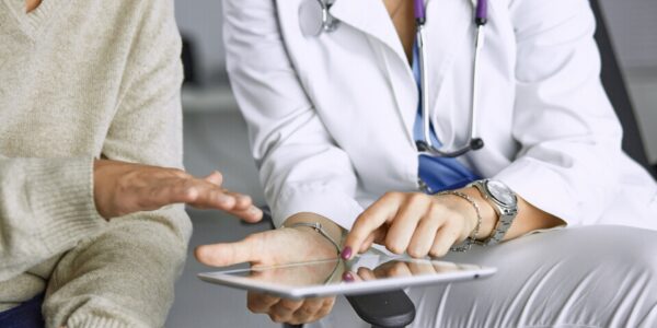 Eine Ärztin zeigt einem Patienten etwas auf einem Tablet.