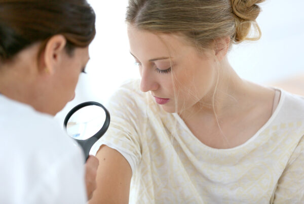 Eine Frau wird von einer Ärztin mit einer Lupe untersucht